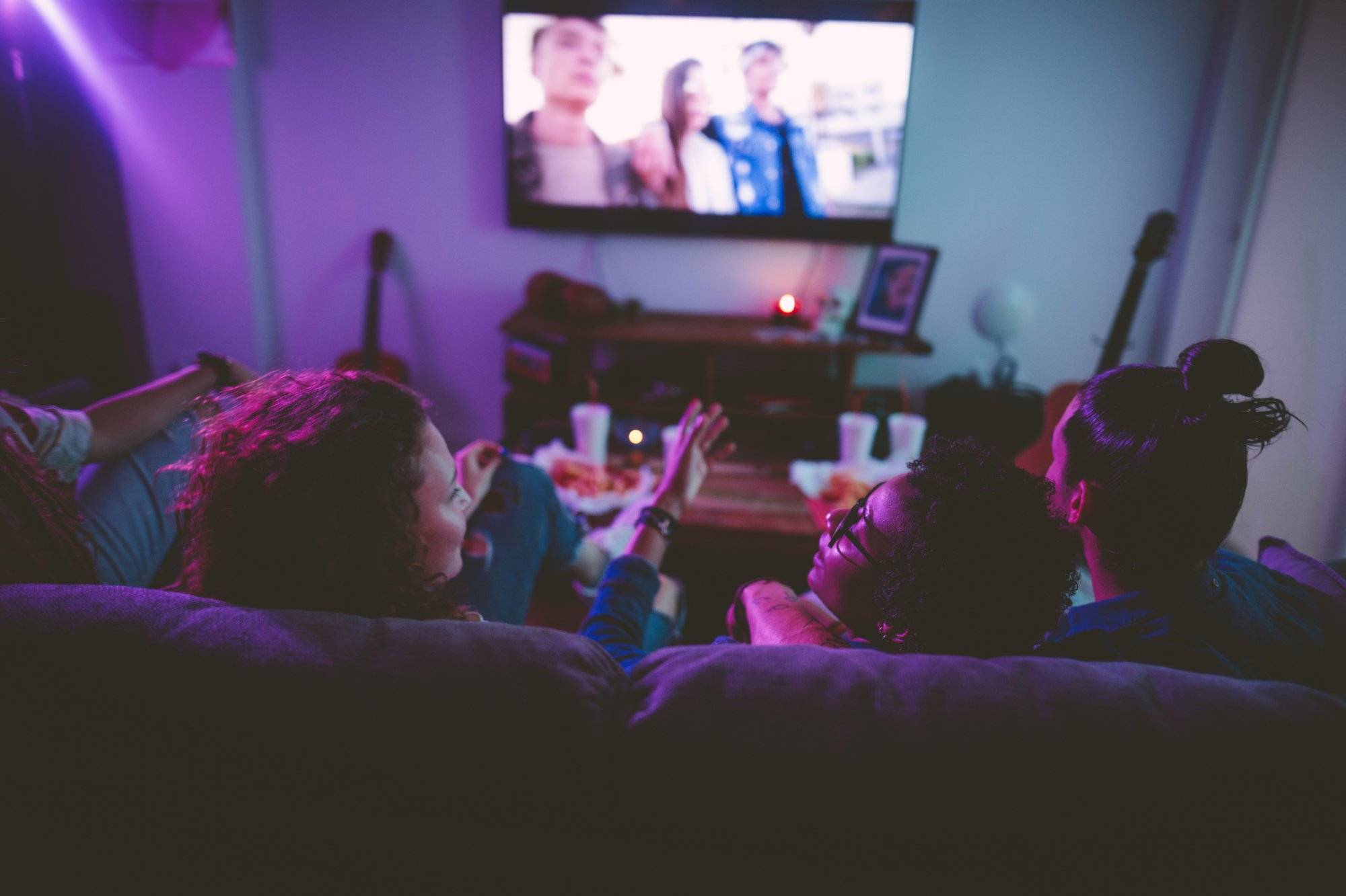 Multi-ethnic teenage friends watching TV together at hangout house Multi-ethnic teenage friends watching TV together at hangout house