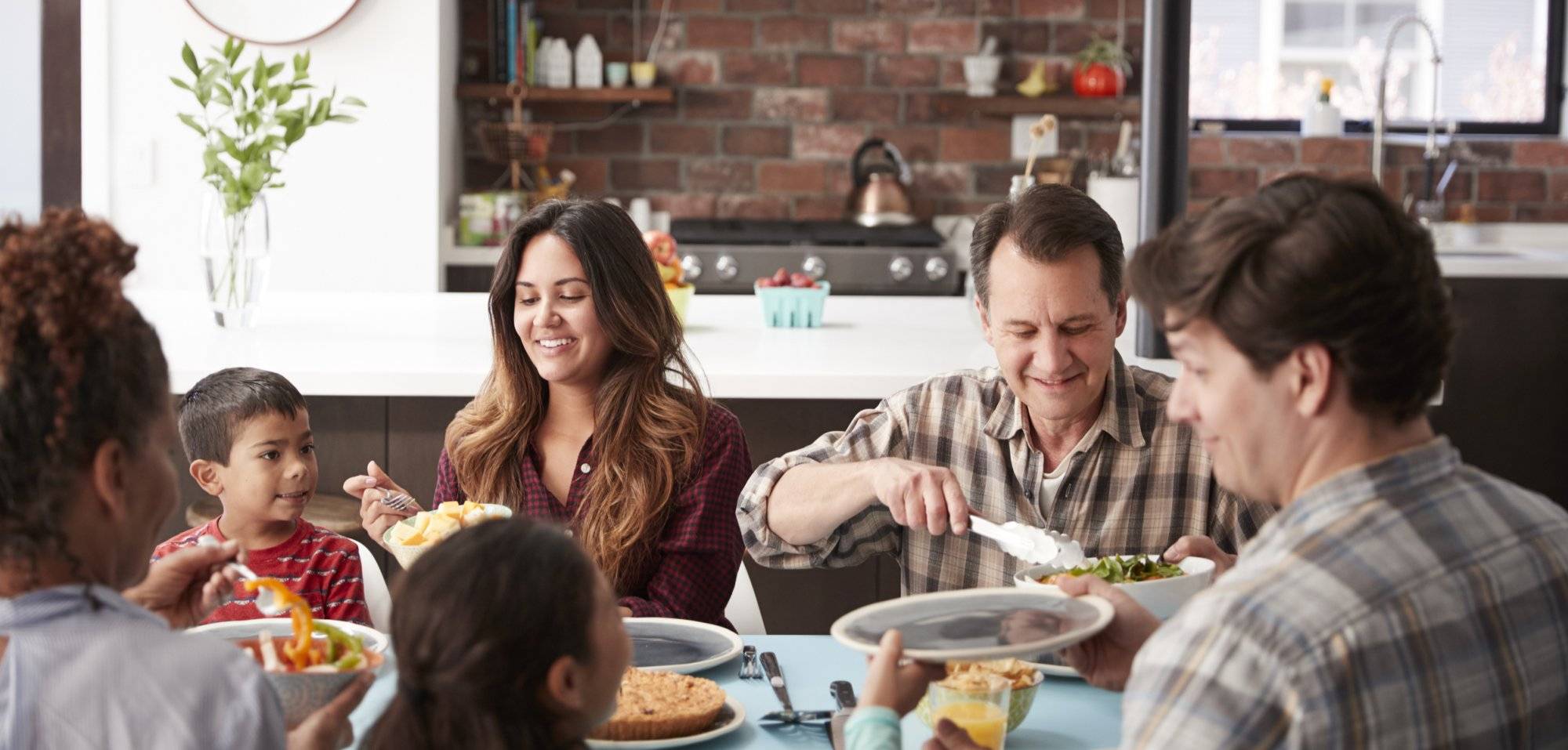 Multi Generation Family Enjoying Meal Around Table At Home Together