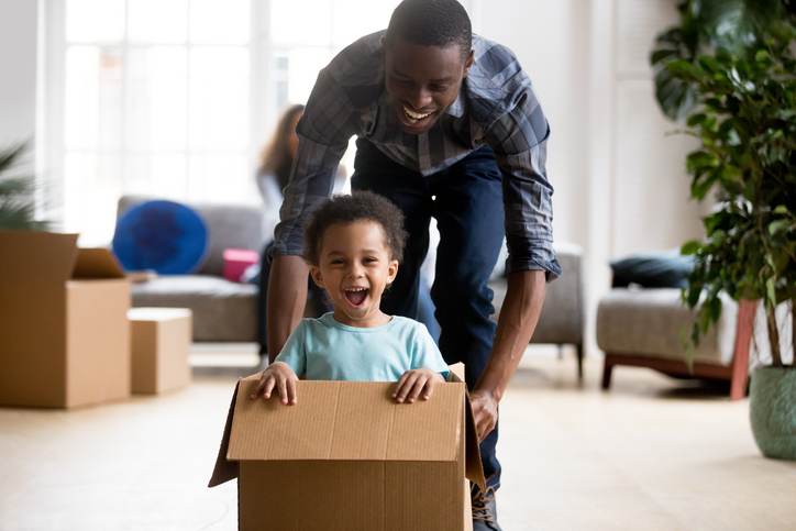 Black father and son playing with box at home