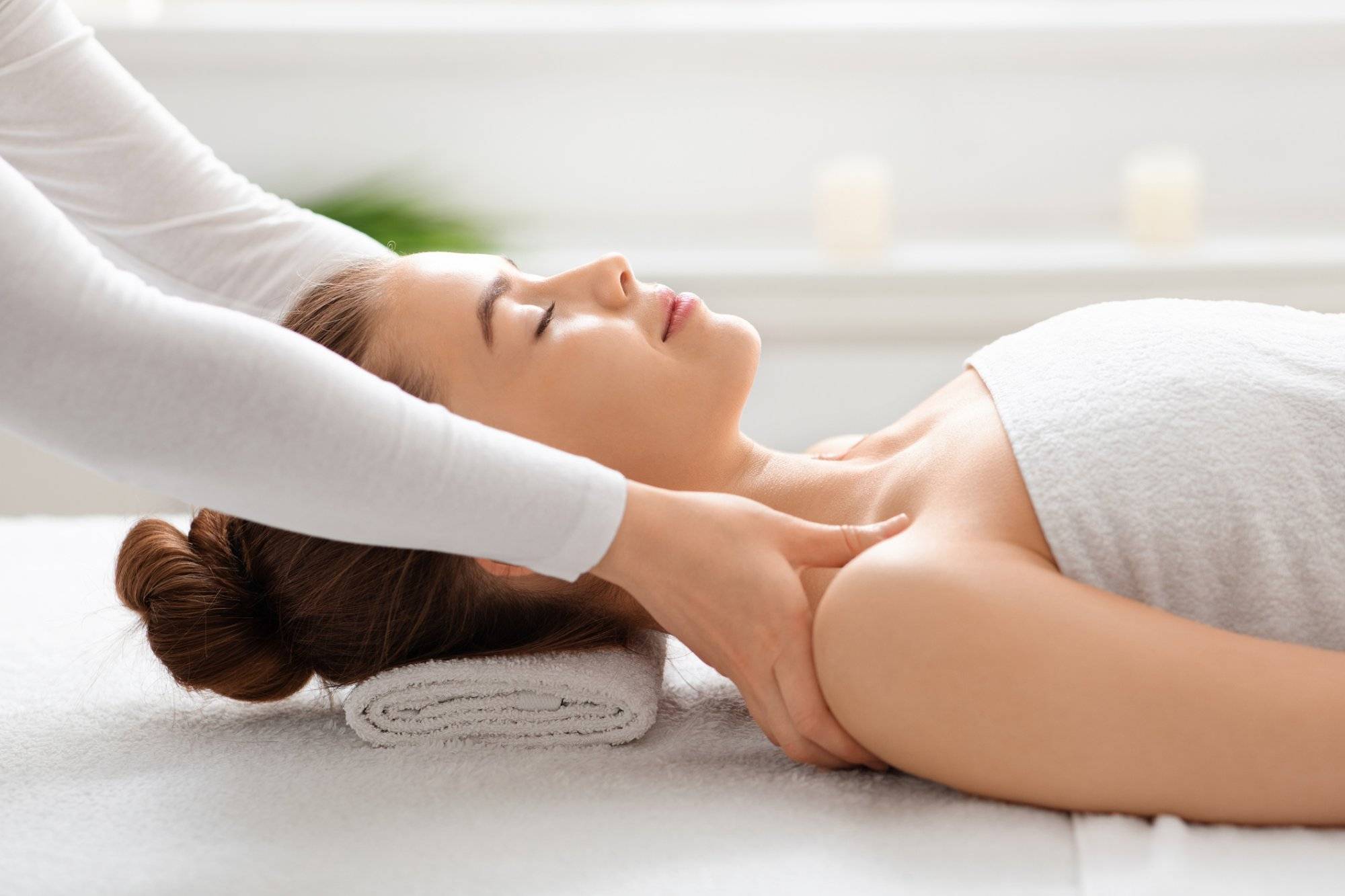 Side view of peaceful young lady having healing body massage Side view of peaceful young lady having healing body massage