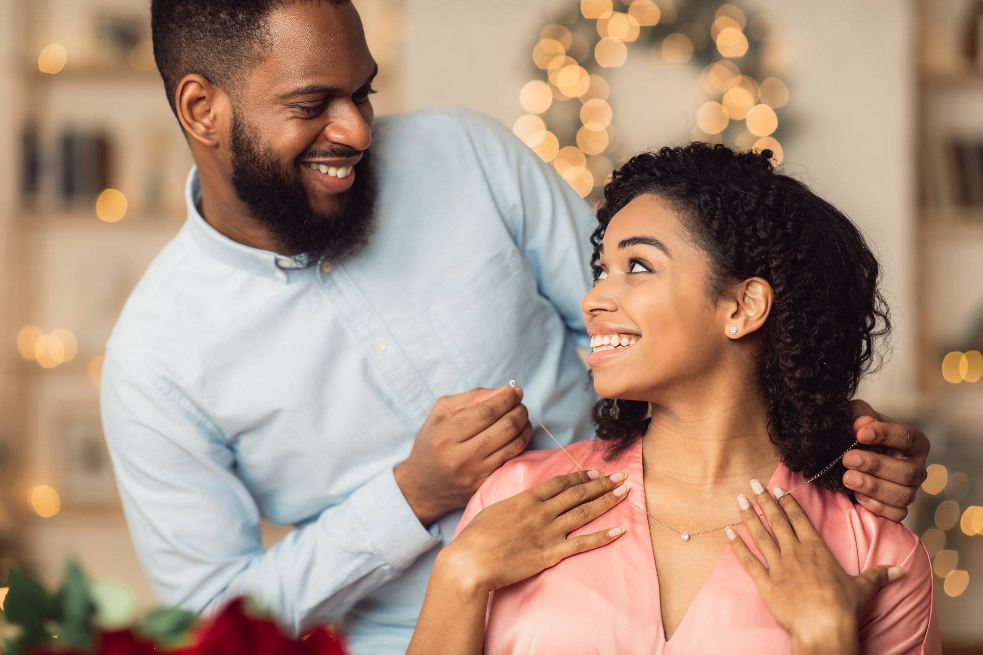 Young black guy wearing necklace on his smiling woman