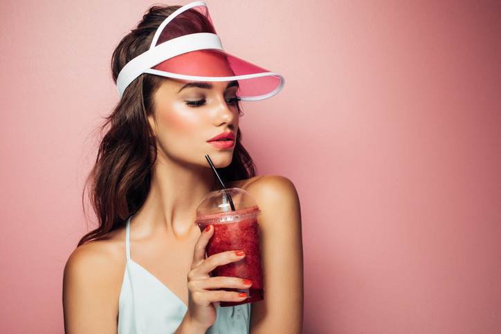 Fashion pretty cool girl drinks from cup over pink background Fashion pretty cool girl drinks from cup over pink background