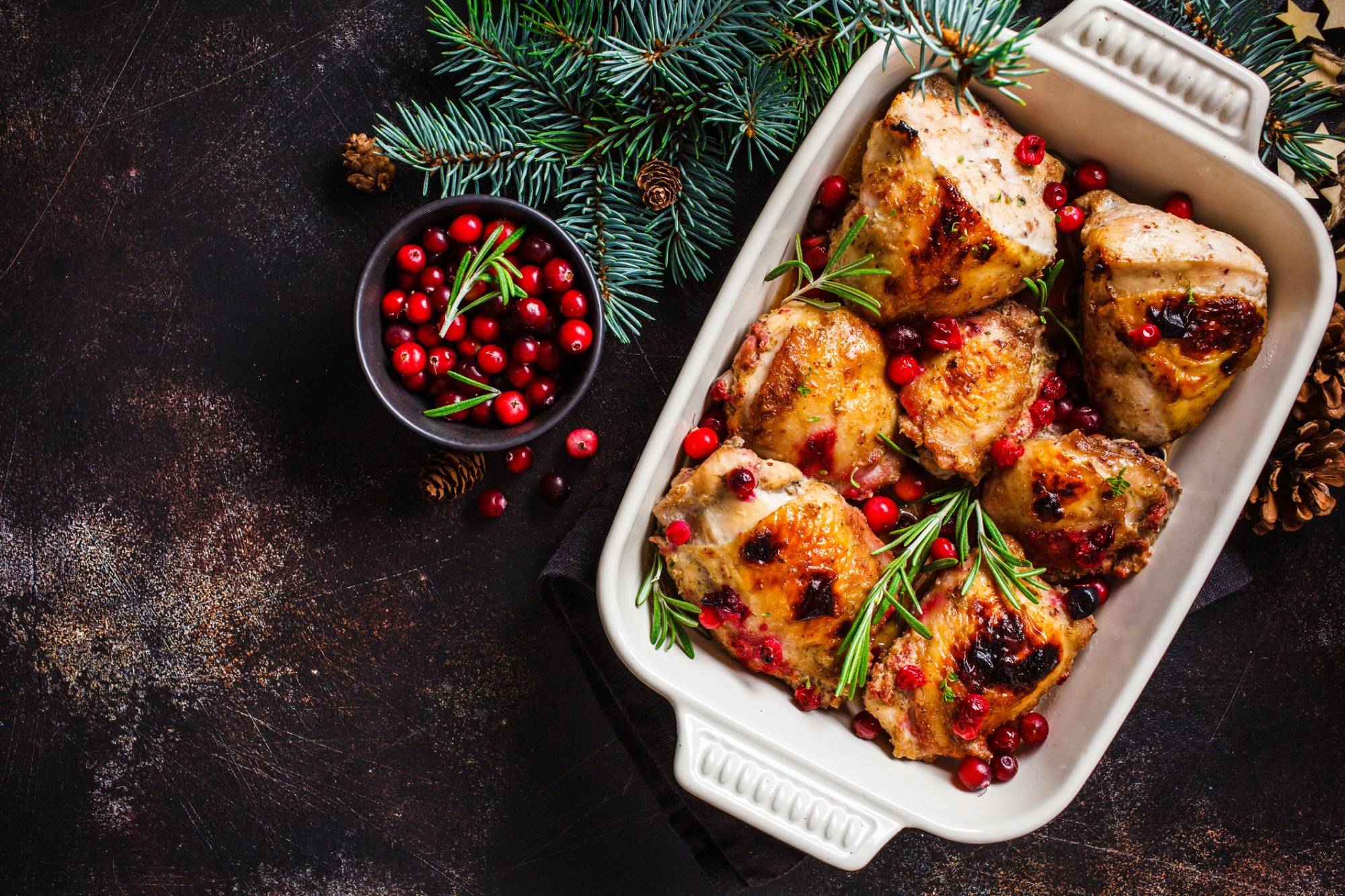 Christmas food. Chicken meat baked with cranberries and rosemary in the oven dish, top view.